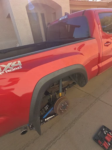 Technician loosening lug nuts with an impact wrench during a roadside tire change in Phoenix, AZ