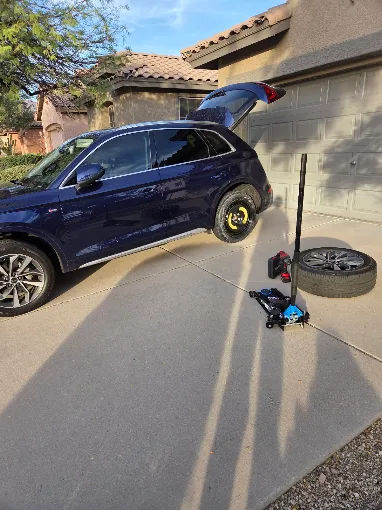 Gloved hand checking tire pressure with a gauge during mobile tire inflation service in Phoenix, AZ